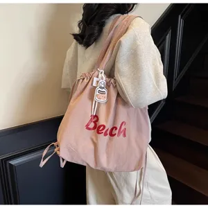 Vue détaillée du sac cabas fourre-tout en nylon rose avec imprimé plage et charm mignon.