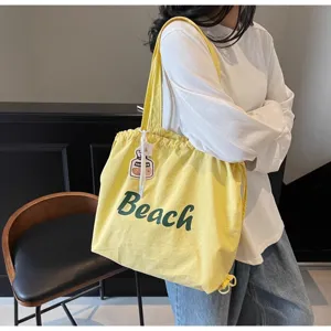 Vue détaillée d'un sac cabas en nylon jaune avec inscription Beach et cordon de serrage.
