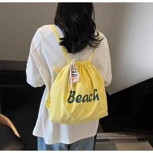 Vue détaillée du sac à dos à cordon en nylon jaune décontracté avec imprimé et pendentif.