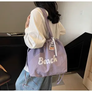 Vue détaillée du sac porté épaule en nylon décontracté avec inscription Beach et cordon.