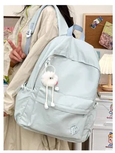 Detail view of light blue casual backpack with cute fluffy monster pendant and front pocket.
