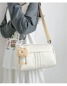 Casual canvas shoulder bag for women with plush pendant, lightweight daily travel tote.