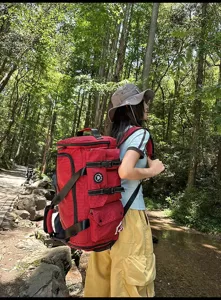 Outdoor detail shot of a red grid convertible duffel backpack worn by a hiker in forest.