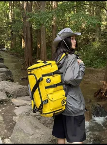 Detailed view of large yellow outdoor travel backpack in forest, durable waterproof fabric.