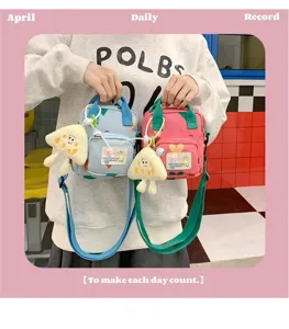 Cute cartoon canvas crossbody bag with plush pendant, stylish daily shoulder bag for women.
