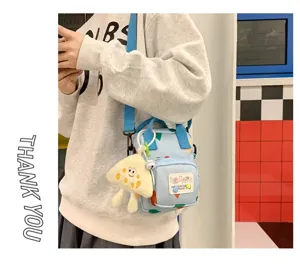 Detailed view of cute canvas crossbody bag with plush pendant and adjustable blue shoulder strap.