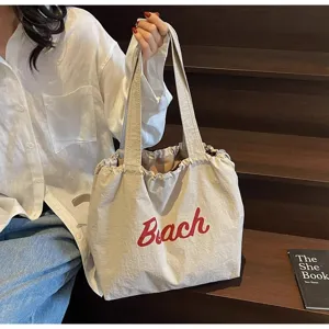 Detalle de bolso tote de lona, bolso de hombro casual con cordón y estampado rojo.