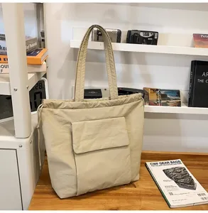 Gedetailleerd overzicht van de stijlvolle beige tote bag met handige voorzak en koord.