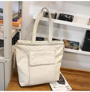 Close-up van de beige canvas tote tas met voorvak, trekkoordsluiting en praktische details.