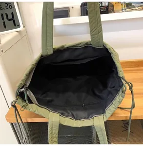 Gedetailleerd overzicht met de ruime binnenvoering en ritszak van de groene tote bag.