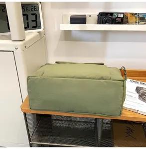 Gedetailleerd overzicht van de casual groene canvas schoudertas in een gezellige kamer.