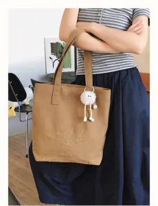 Canvas tote bag detail showcasing large capacity, shoulder strap, and cute fluffy charm pendant.