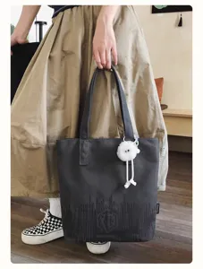 Dark gray canvas tote bag detail, featuring large capacity, soundwave print and cute plush pendant.