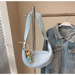 Detailansicht einer lässigen hellblauen Crossover-Tasche mit süßem Anhänger für Damen.