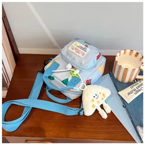 Detailed view of cute blue canvas crossbody bag with plush charm on wooden desk setup.
