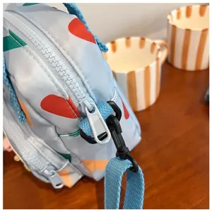 Close-up of light blue canvas crossbody bag detail, cute colorful print, zipper and strap.
