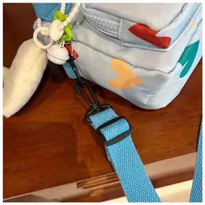 Close-up detail of light blue canvas crossbody bag showing colorful heart pattern and strap.