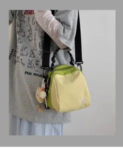 Detailed view of the stylish green and yellow canvas shoulder bag with lovely charm accessory.