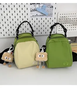 Lightweight canvas shell crossbody bag with cute plush charm and braided handle details.