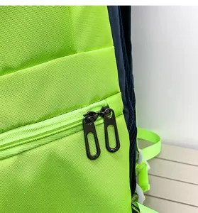 Backpack detail shot showing the durable green and blue nylon fabric with dual metal zippers.