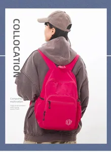 Detail shot of the minimalist pink waterproof casual backpack showing front pocket and fabric texture.