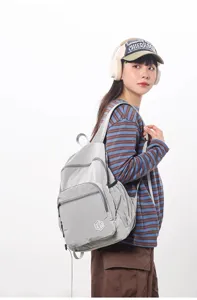 Detailed view of lightweight gray grid backpack worn by model, showcasing front pocket and strap.