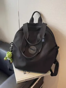 Grand sac à dos noir décontracté en nylon avec porte-clés peluche et poignées pratiques.