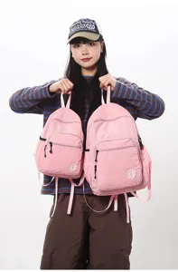 Detailed view of lightweight pink folding backpacks held by model, showing portable design.