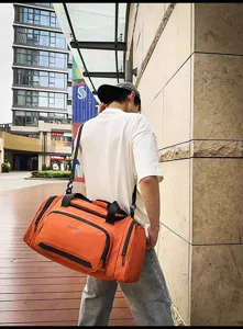 Vue détaillée du grand sac de voyage orange montrant la sangle et la poche avant.