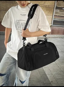 Vue détaillée du sac de voyage noir avec bandoulière et grande capacité de rangement.