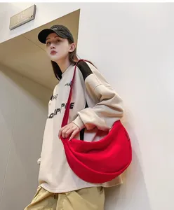 Detailed view of the stylish red crescent shoulder bag worn in daily casual outfit scene.