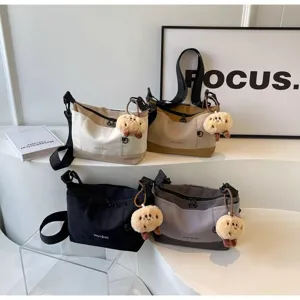Details of canvas messenger bag with cute plush pendant, multi-pocket retro crossbody style.