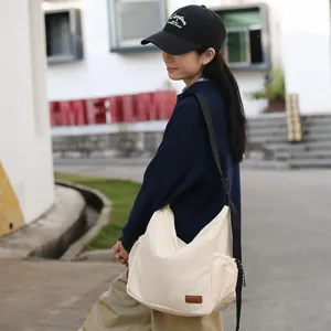 Detail shot of the canvas messenger bag worn by a model outdoors, highlighting daily casual style.