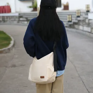 Canvas crossbody bag detail showing large capacity design, wide strap and casual daily use style.