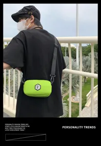 Waterproof green crossbody bag detail shot, adjustable black strap, urban street style.