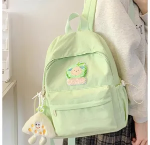Dettaglio zaino casual verde chiaro carino con ciondolo in peluche e toppa ricamata.