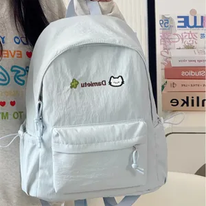 Close-up of light blue casual backpack with cute cat embroidery and functional front pocket.