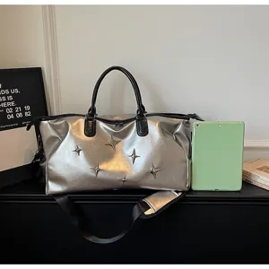 Silver metallic travel duffel bag detail, featuring star metal studs and black handles.