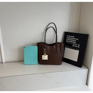 Detailansicht einer braunen großen Shopper Schultertasche mit schickem Plüschanhänger im Trend.