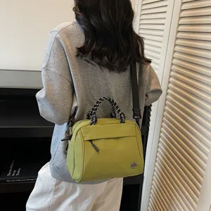 Primo piano di una borsa verde casual con manici in corda nera e bianca e tracolla regolabile.