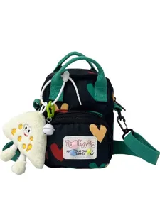 Cute canvas crossbody bag for women, dark heart print with plush pendant and green handles.