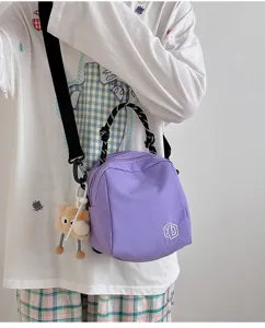 Purple canvas crossbody bag detail shot, featuring black braided handle and cute bear charm.