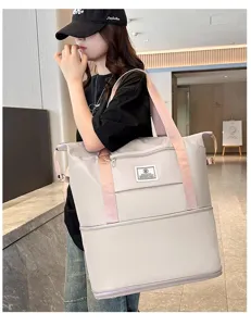 Grande borsa da viaggio in grigio chiaro con manici rosa, tenuta da modella in interno.