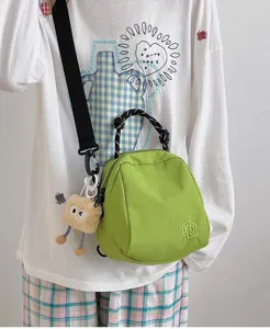 Green shell crossbody bag for women, canvas shoulder handbag with cute plush pendant and handle.