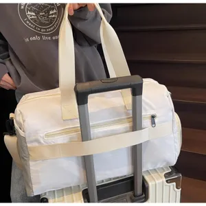 Vista dettagliata della grande borsa da viaggio bianca con fascia per valigia e manici robusti.
