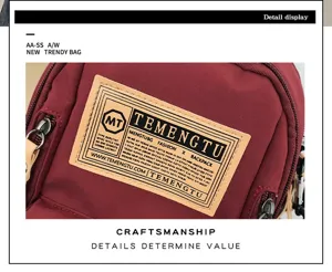 Canvas chest bag detail view showing front brand label, durable maroon fabric and hardware.