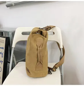 Détail du sac à bandoulière en toile kaki robuste avec poignée pratique et sangle réglable.