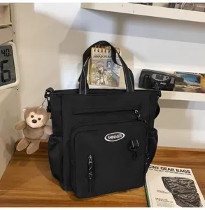 Black multi-pocket canvas tote bag with shoulder strap and cute monkey charm for daily school use.