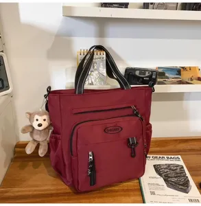 Large capacity red canvas tote bag with multiple pockets, ideal for students and daily use.