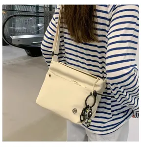 Detail view of the casual nylon crossbody bag, showing lightweight texture, strap, and cute pendant.